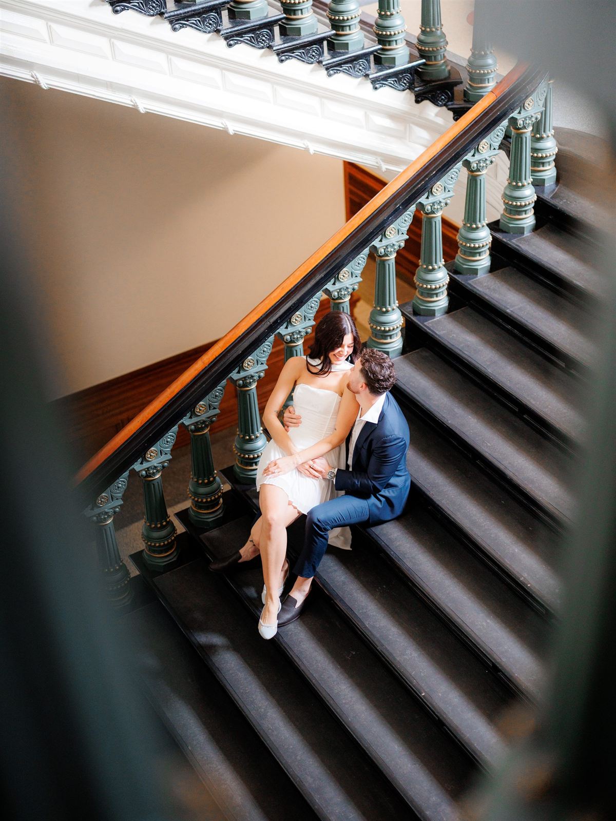 A couple embrace on a sweeping staircase, seen from above