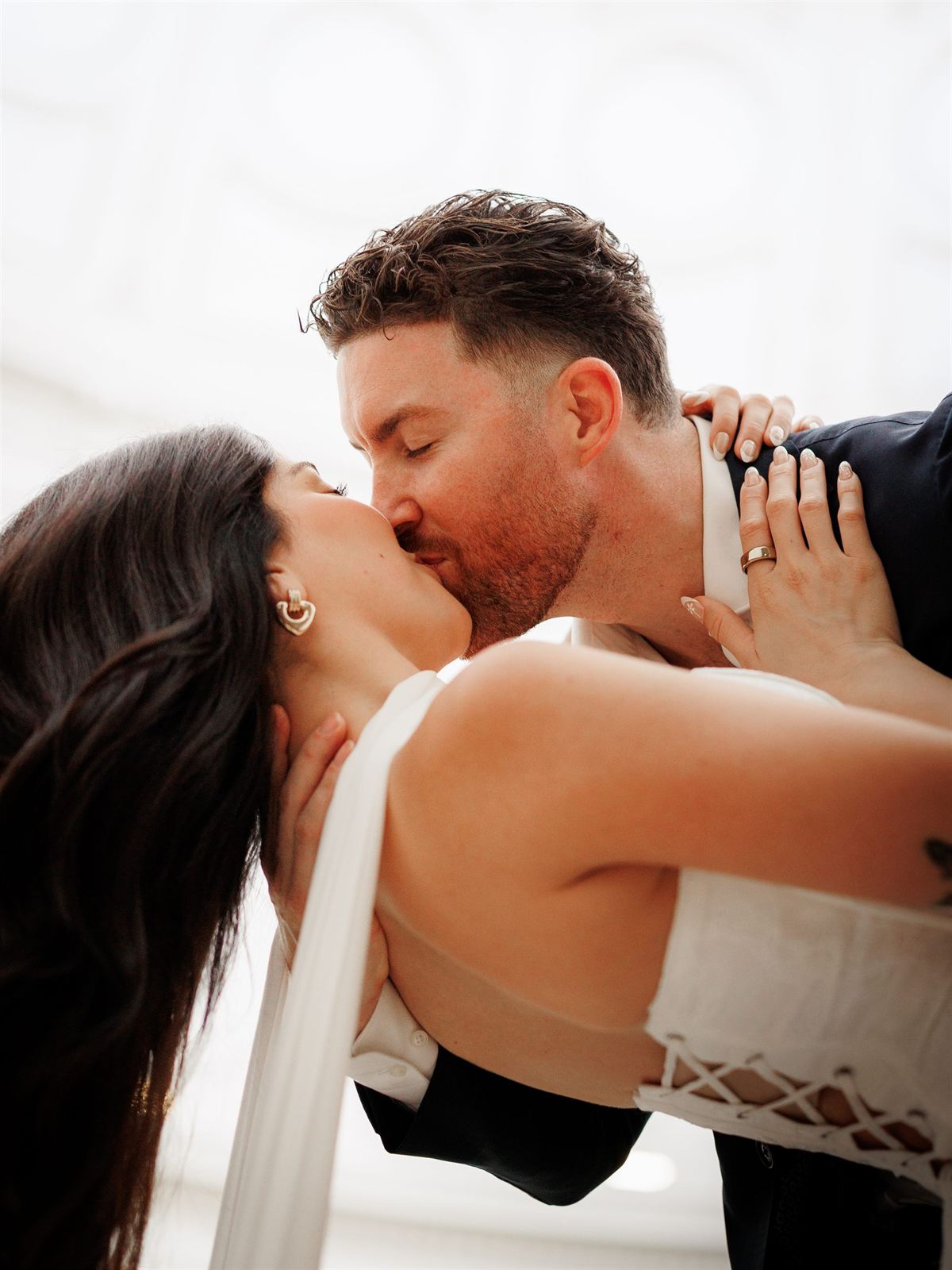 A groom dips his partner into a kiss