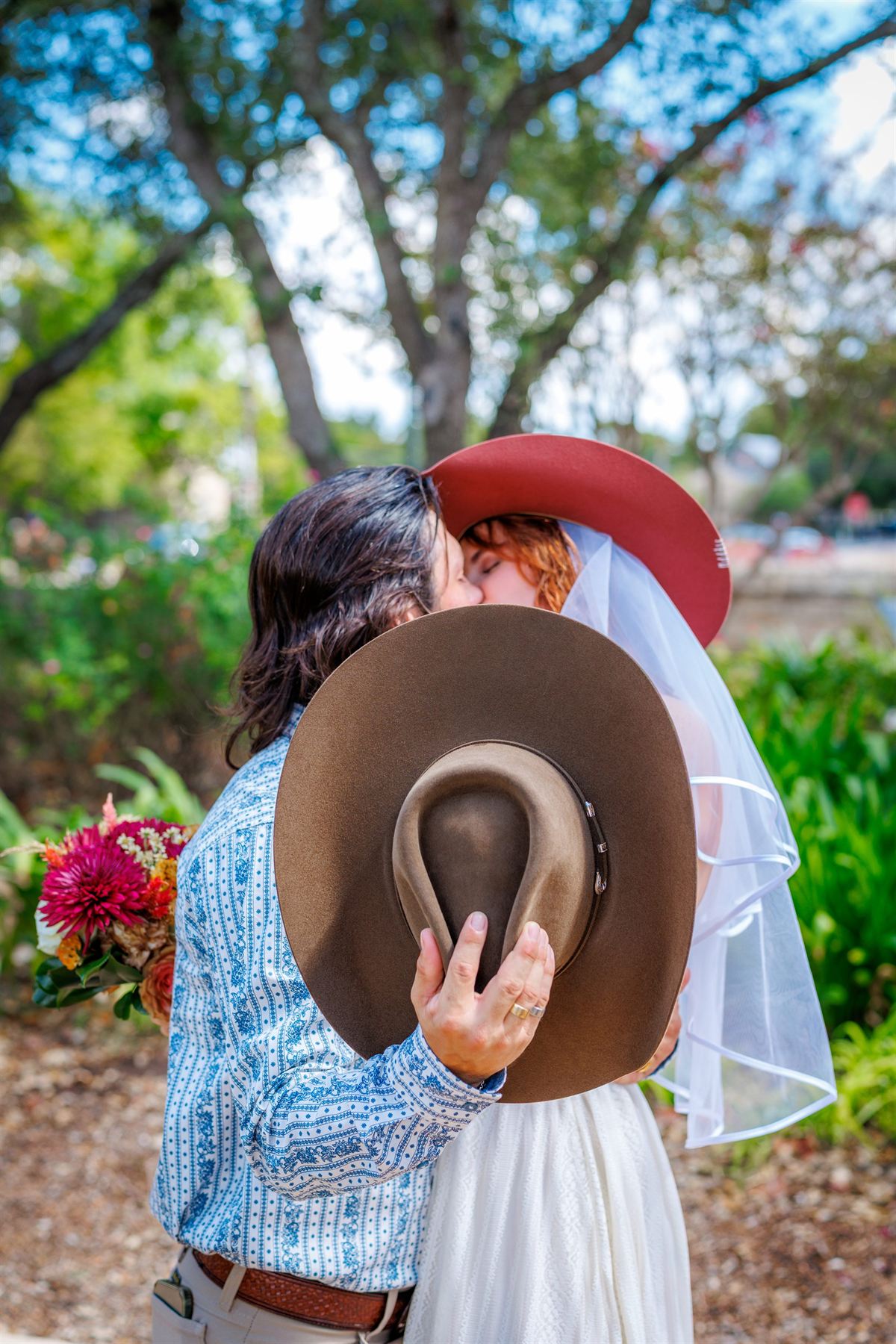 A couple kiss behind a cowboy hat