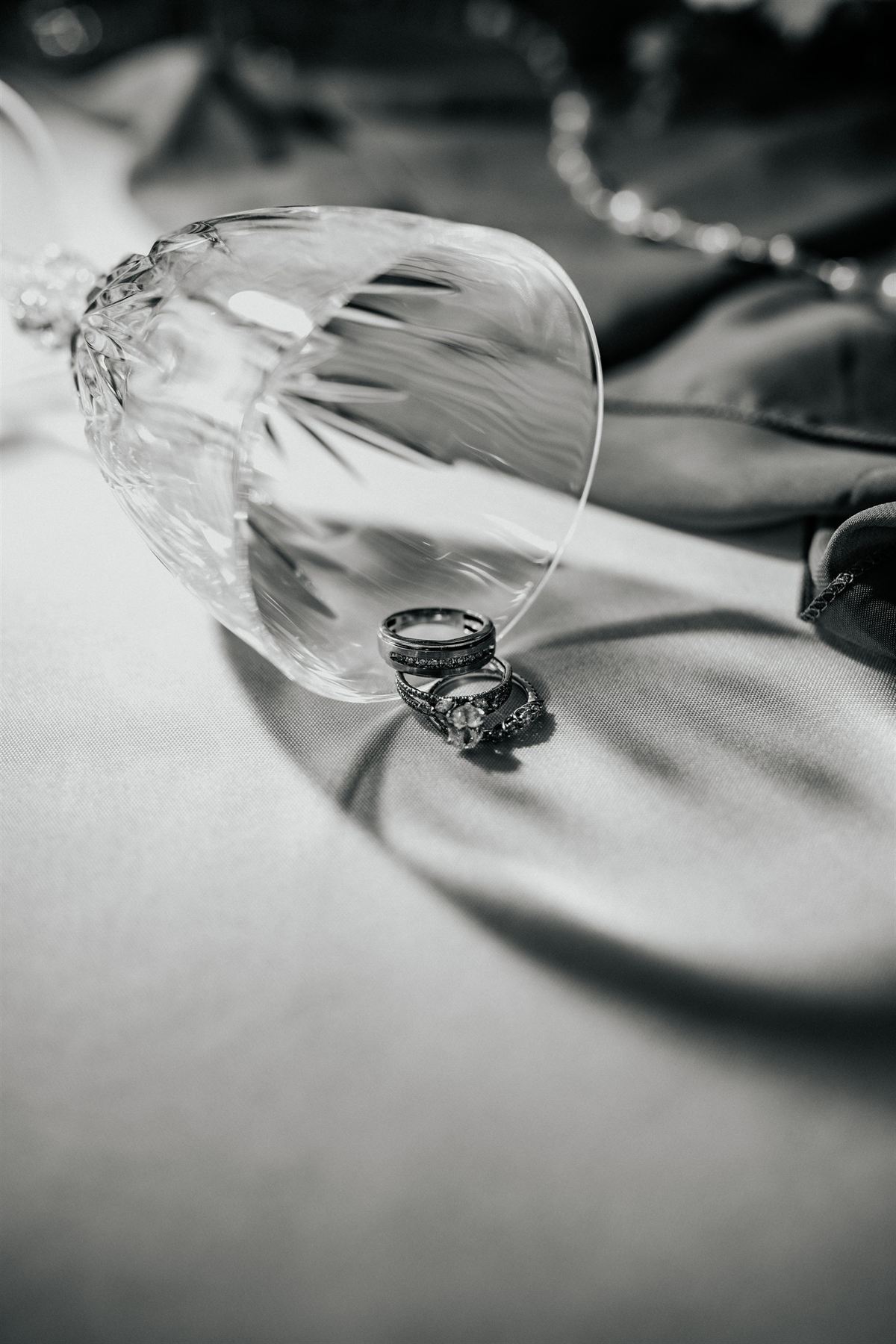 Wedding rings resting beneath a crystal glass, in black and white