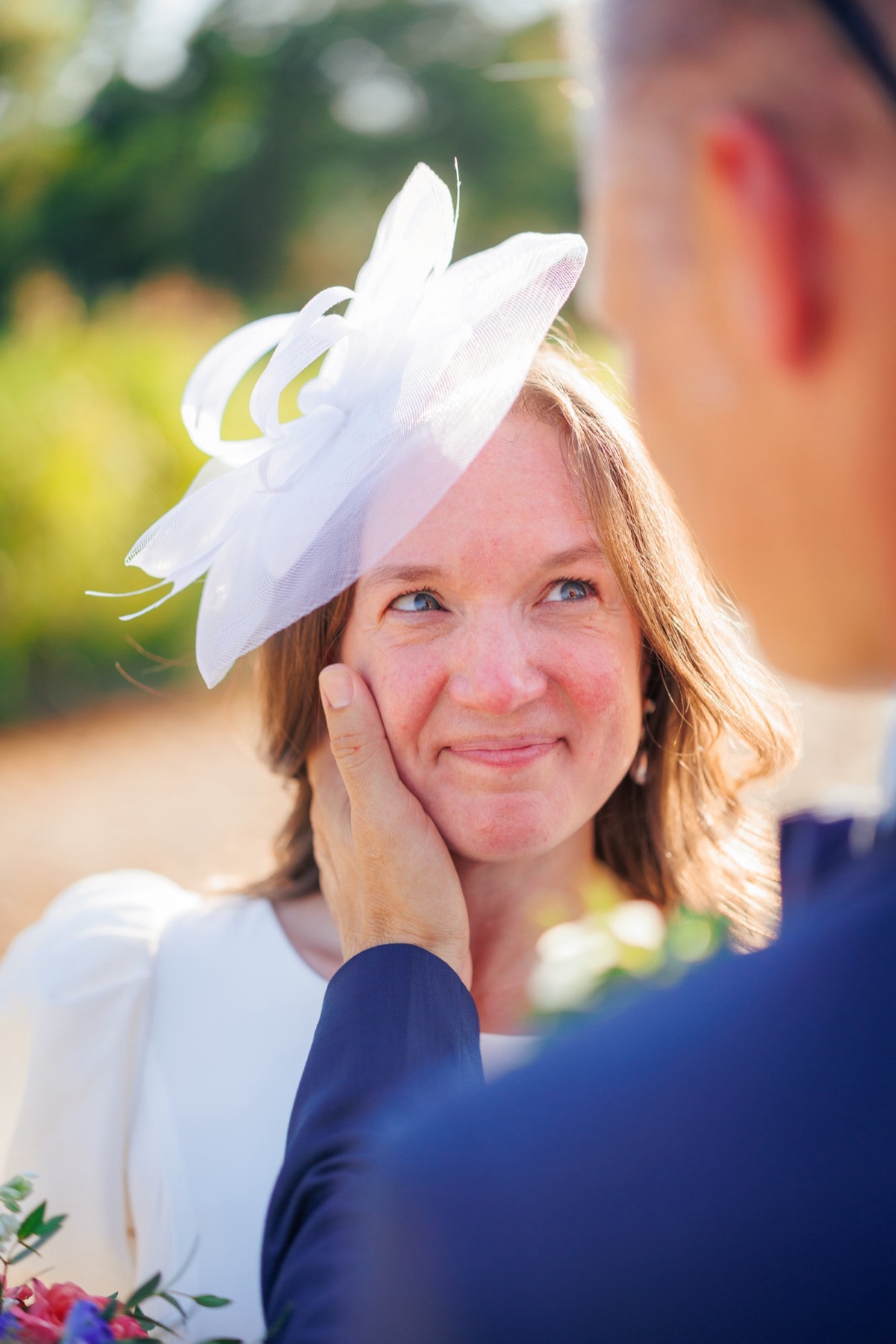 The groom cups his bride's cheek as she smiles up at him